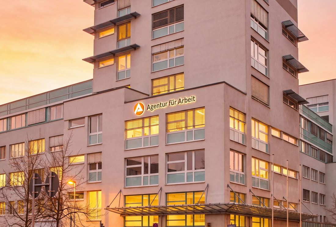 Das Gebäude der Agentur für Arbeit Dresden am Abend mit erleuchteten Fenstern